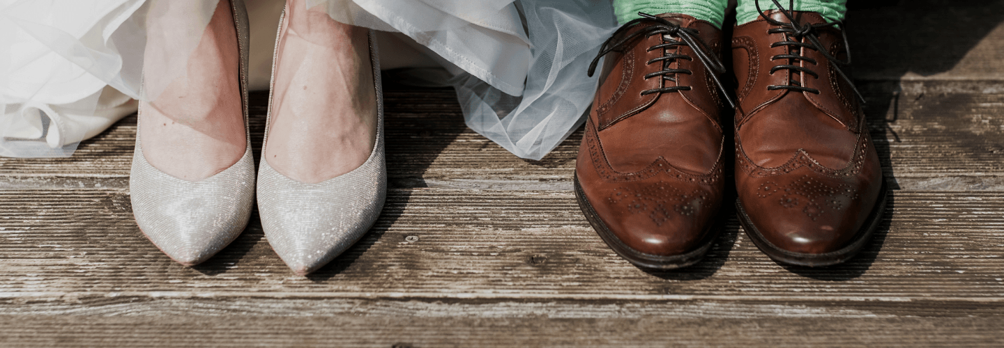Los zapatos de la novia y del novio, lado a lado sobre un piso de madera
